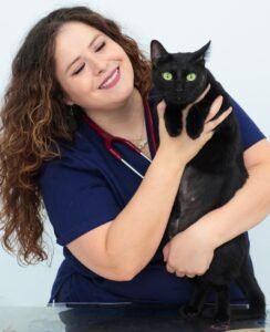Luz Elide Bolio, veterinaria de Alebrije Centro Veterinario sosteniendo a un gato negro durante una consulta.